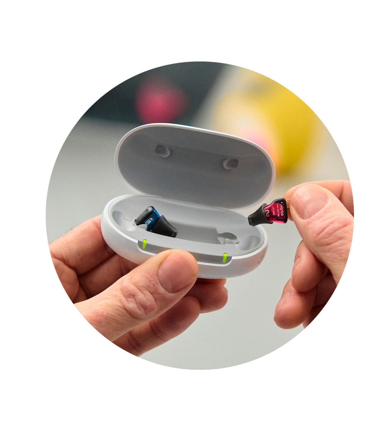 Hände setzen MiniHörgeräte in Ladestation ein
